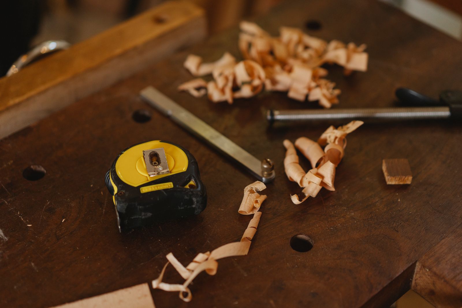 Tape measure, woodworking tools and curled wood shavings on a timber workbench