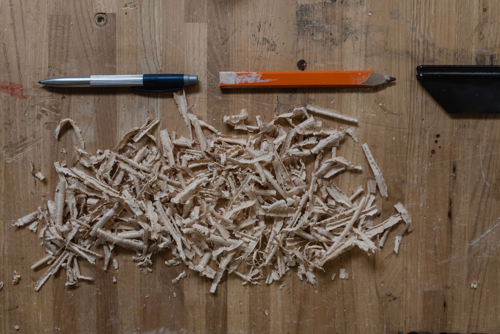 Carpenter’s pencil, marking tools and wood shavings on a wooden surface