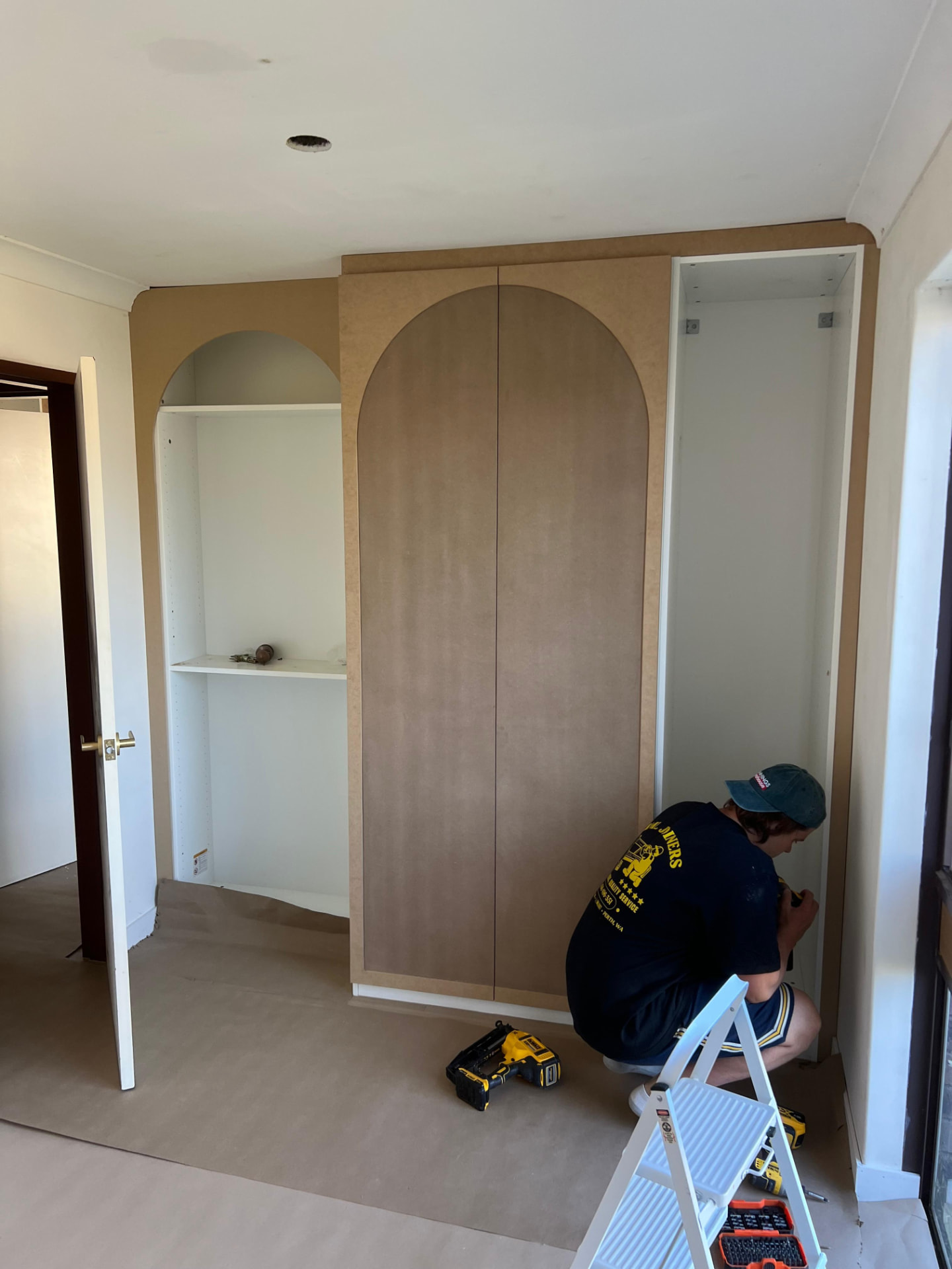 Jono fitting an arched built-in wardrobe, with arched open shelving beside the doors