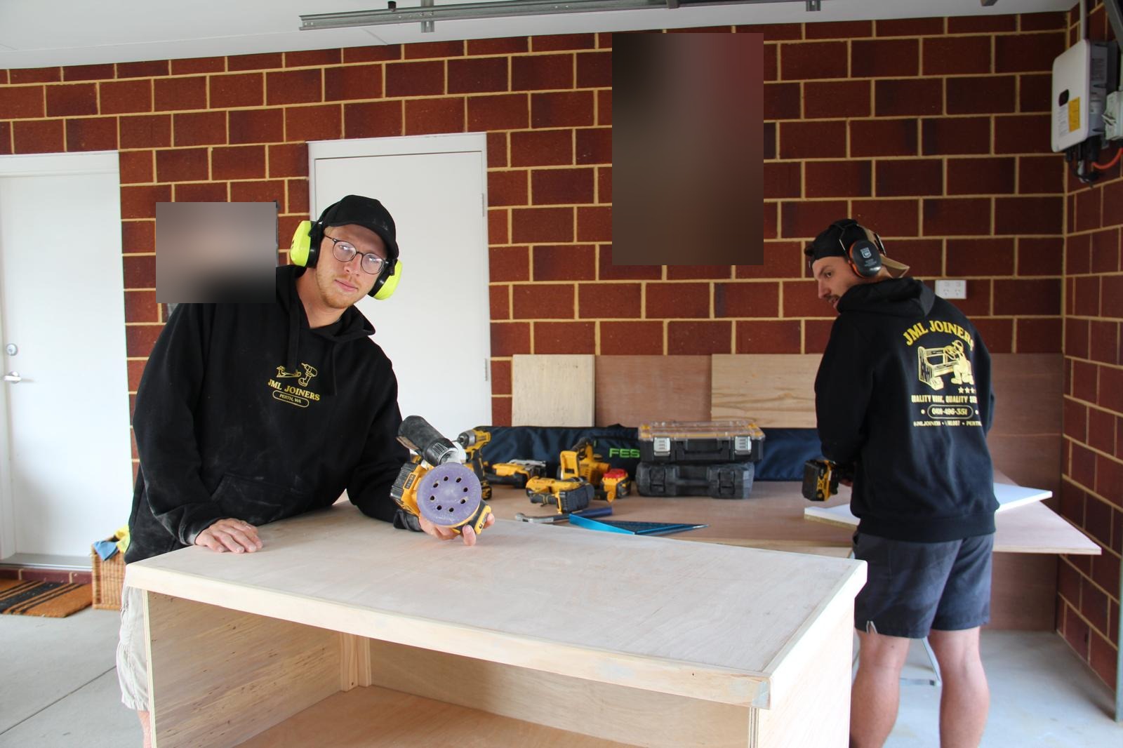 Two joiners preparing a plywood cabinet carcass for finishing